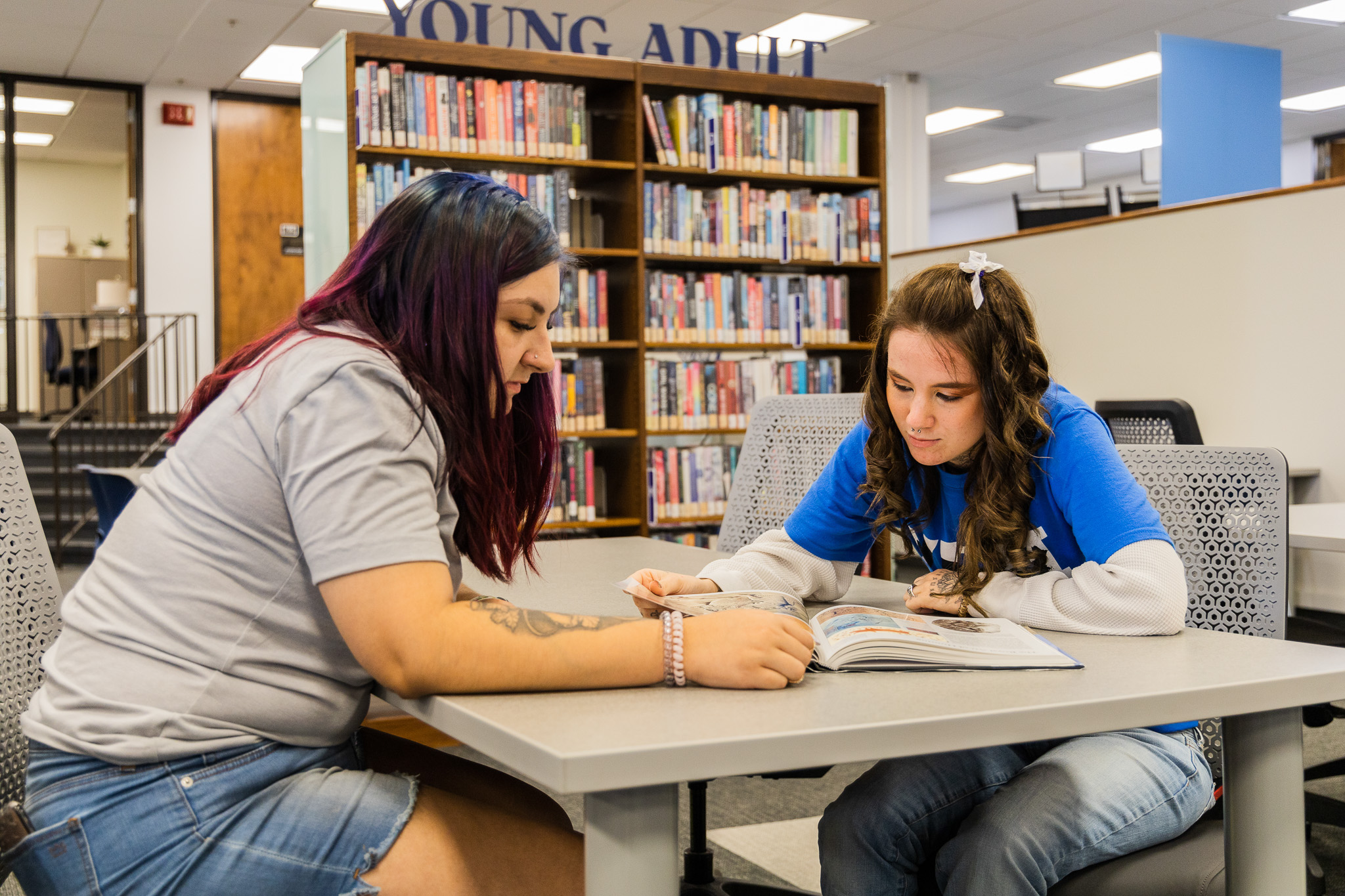 Two female students studying in the library at a table together.