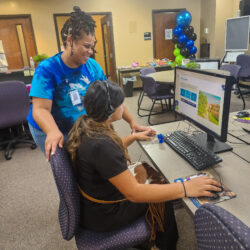 Staff member helps a student complete the financial aid application on a computer.
