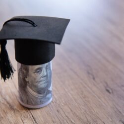 closeup image of graduation cap and money on table