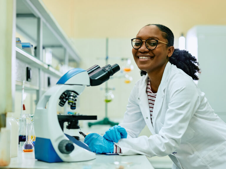 Happy black female scientist in laboratory looking at camera.