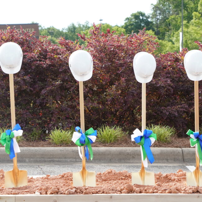 Shovels with hardhats hanging on the handles.