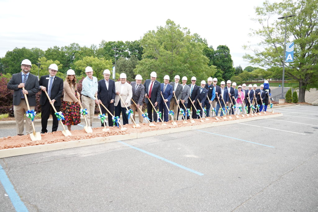 Group of people posing with shovels at the box of dirt, preparing for the ceremonial shoveling.