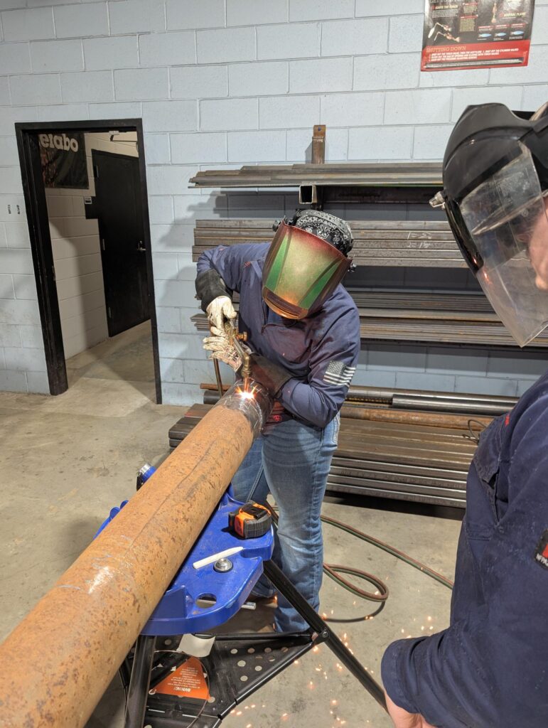 Taylor Tongle practicing her welding skills in CCC's welding shop as her instructor watches.