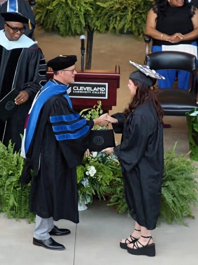 Taylor Tongle receiving shaking hands with and accepting her welding certificate from CCC President Dr. Jason Hurst on stage at CCC's graduation ceremony.